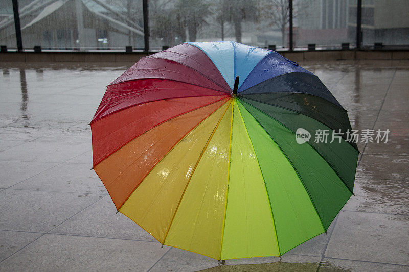 雨点落在彩虹伞上，天以自然为背景