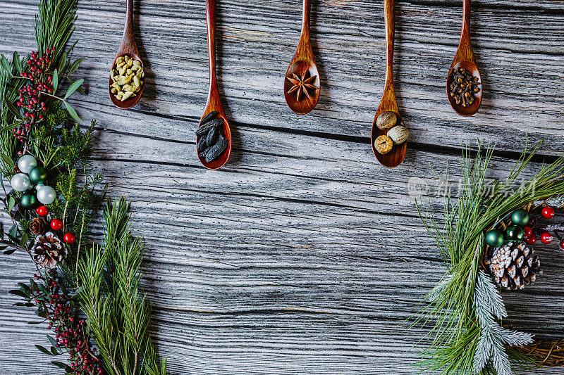 扁平的典型美味的圣诞节和冬季香料在九深色木勺在一排乡村木垃圾背景圣诞装饰与复制空间