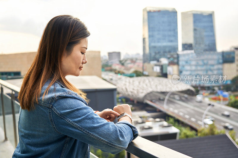 中国上海城市景观中成熟美丽的亚洲女性使用智能手表的肖像