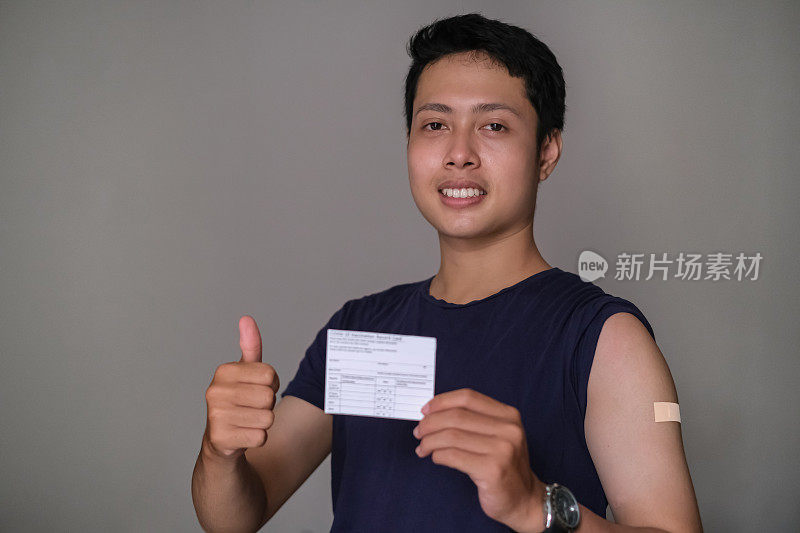 年轻的印尼男子竖起大拇指，展示他的疫苗接种卡