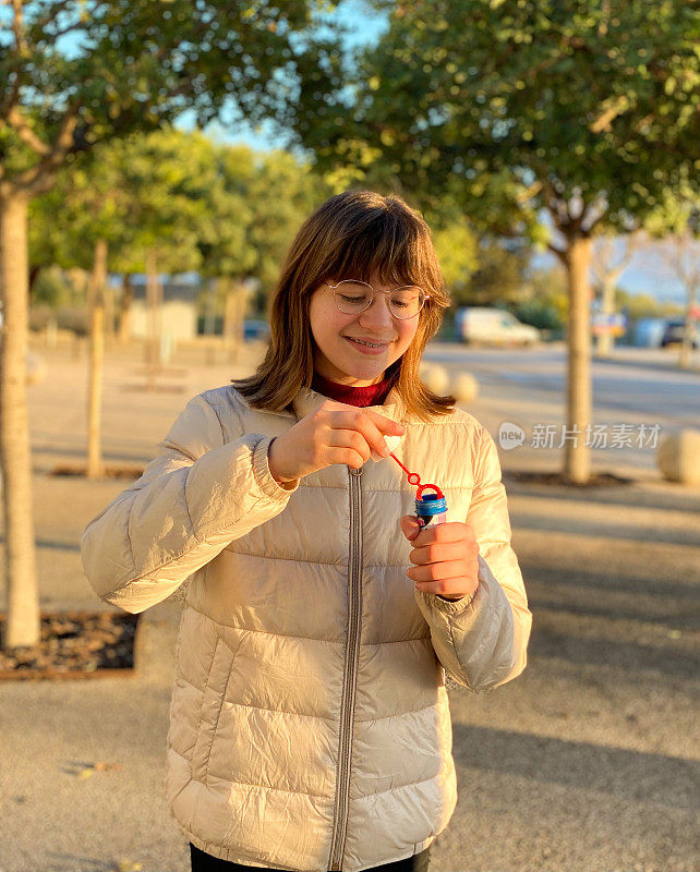 一个十几岁的女孩在街上吹肥皂泡