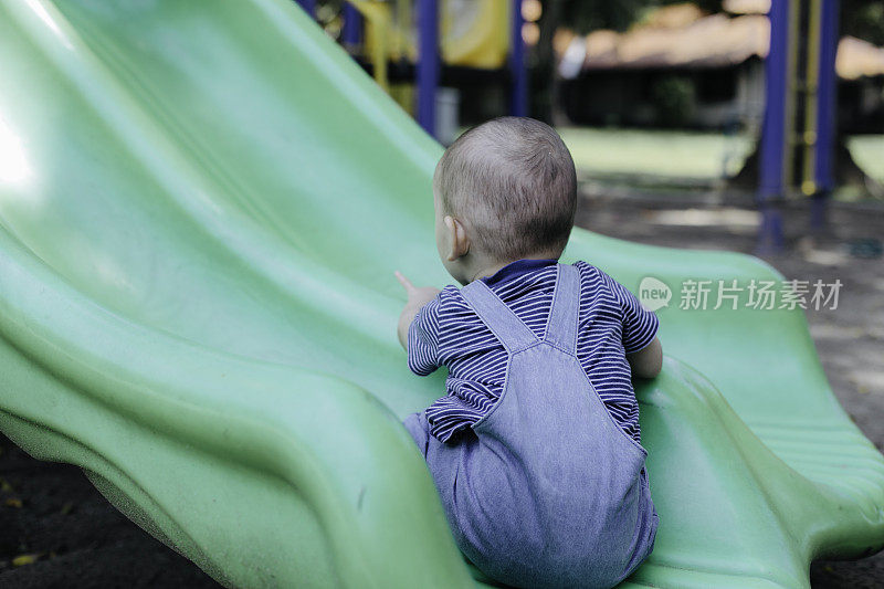 一个小男孩在操场上玩滑梯