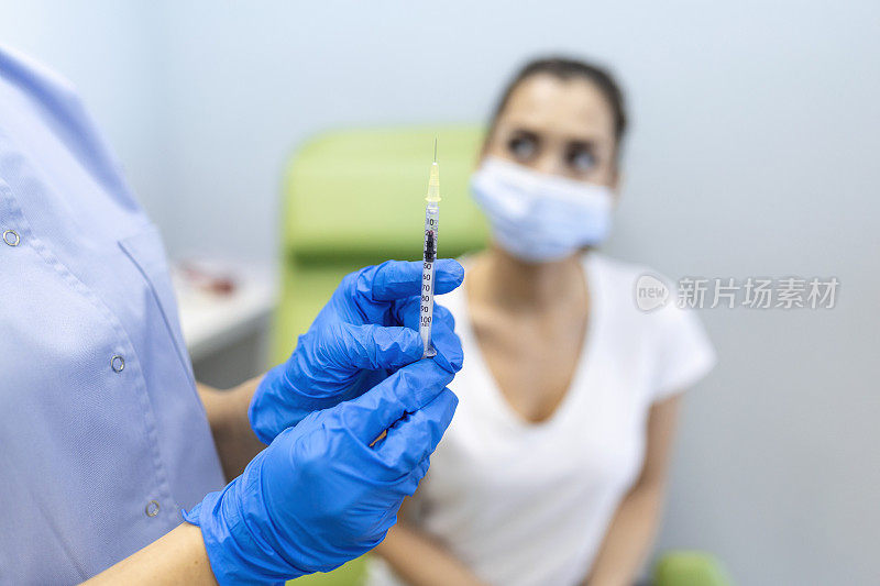 从业人员在诊所为妇女病人接种疫苗。医生在医院给妇女打针。护士手持注射器注射Covid-19或冠状病毒疫苗。注射新冠疫苗概念。