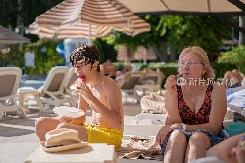 小男孩和奶奶在度假村泳池边吃冰淇淋