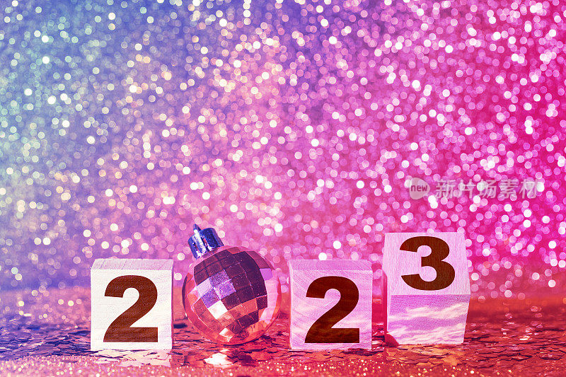 圣诞节和新年霓虹闪烁的背景与数字2023和粉红色的圣诞球与闪亮和模糊的背景