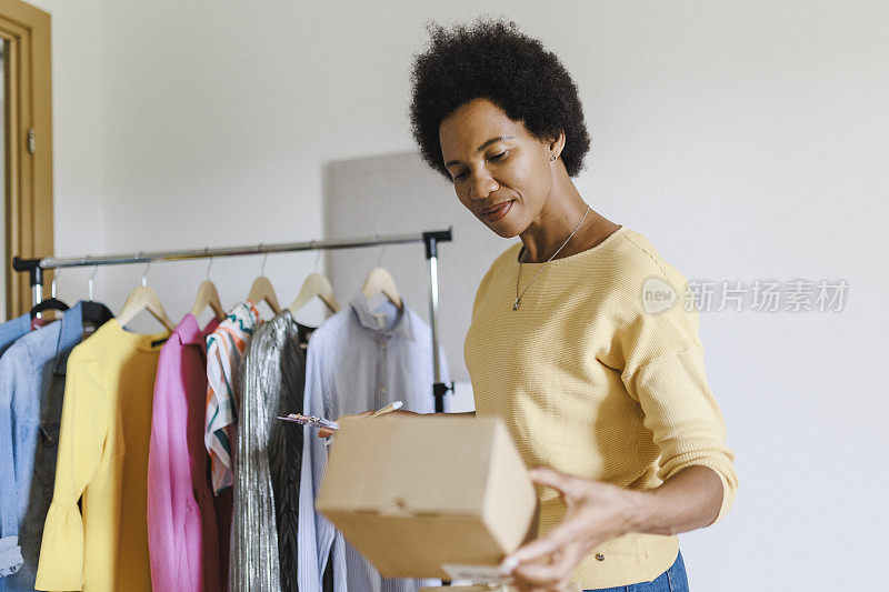 有吸引力的女商人检查订单和包装衣服在纸板箱