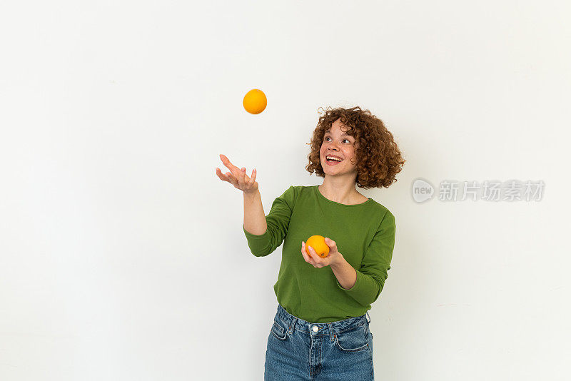 一个快乐的女孩玩橘子的工作室肖像