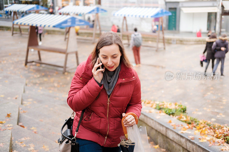 秋天里，女人一边走在城市里，一边打电话