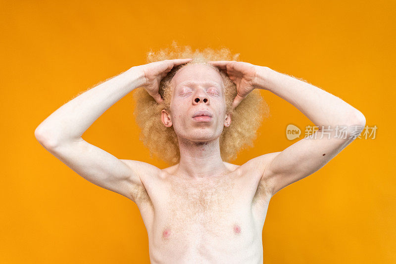 年轻人，手在头发上的橙色背景