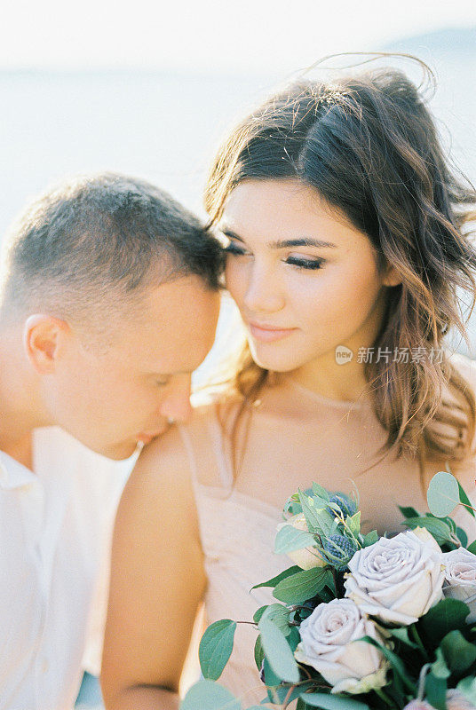 新郎亲吻新娘，新娘肩上扛着一束花。肖像