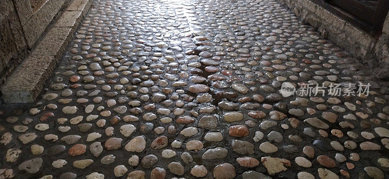 铺路石:由类似大理石的圆形轻石制成的铺路石波斯尼亚和黑塞哥维那萨拉热窝老城的铺好的广场。雨后又湿又亮的漂亮石头。