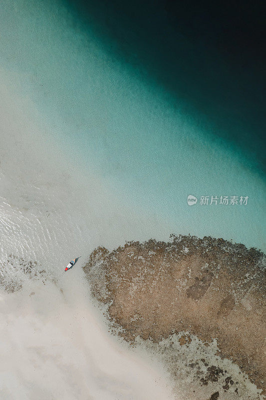 鸟瞰海滩上的船，有清澈的水，沙子的纹理，珊瑚，深水