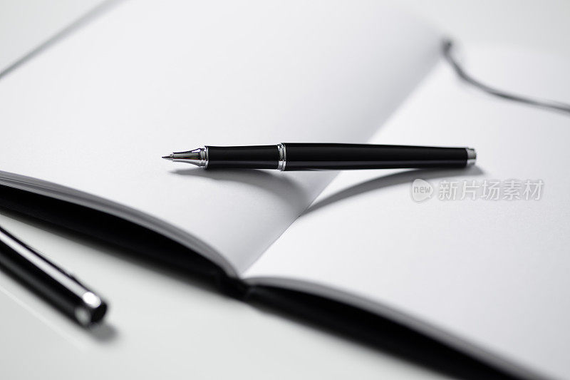 笔记本和黑色钢笔在桌子上