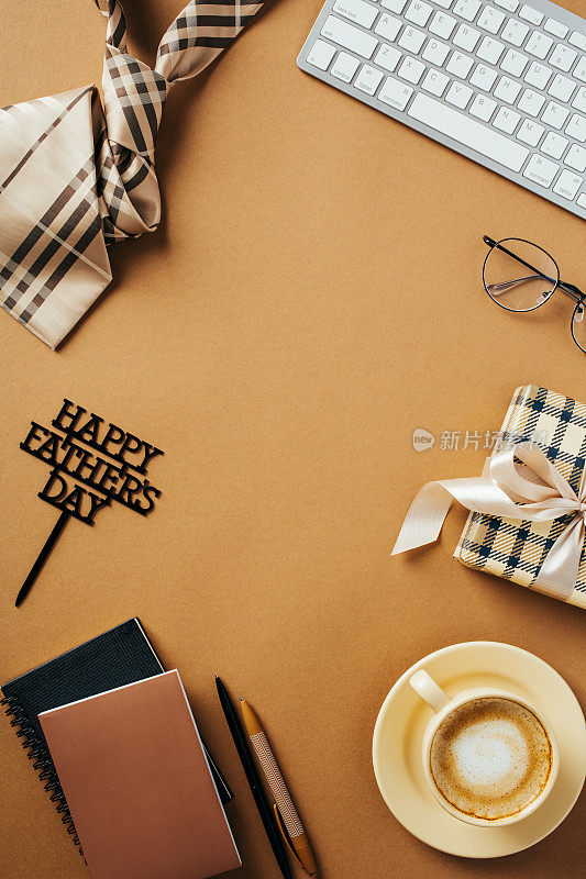 父亲节快乐垂直横幅设计。平面构图与领带，礼品盒，咖啡杯，键盘在棕色背景。复古风格。前视图。