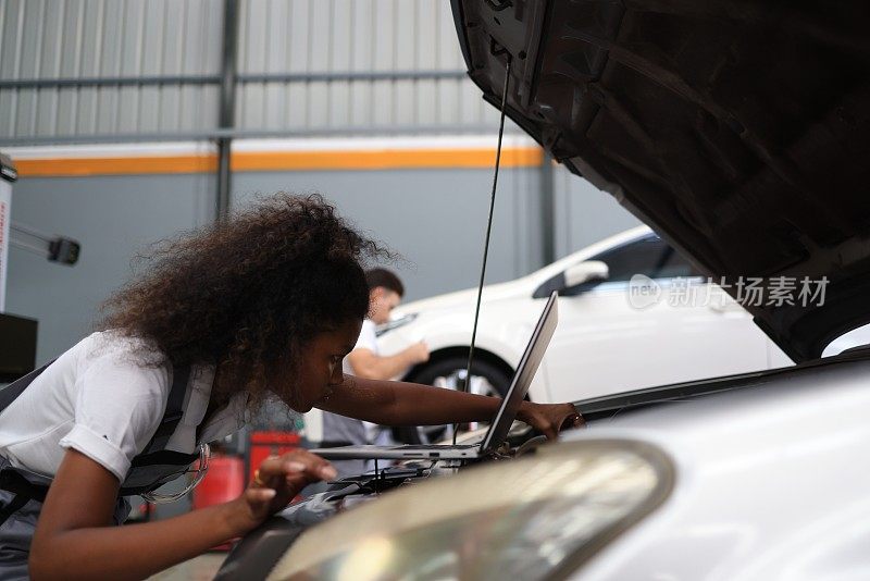 女汽车技师检查机舱进行预防性维修服务。汽车修理厂的维修和保养服务