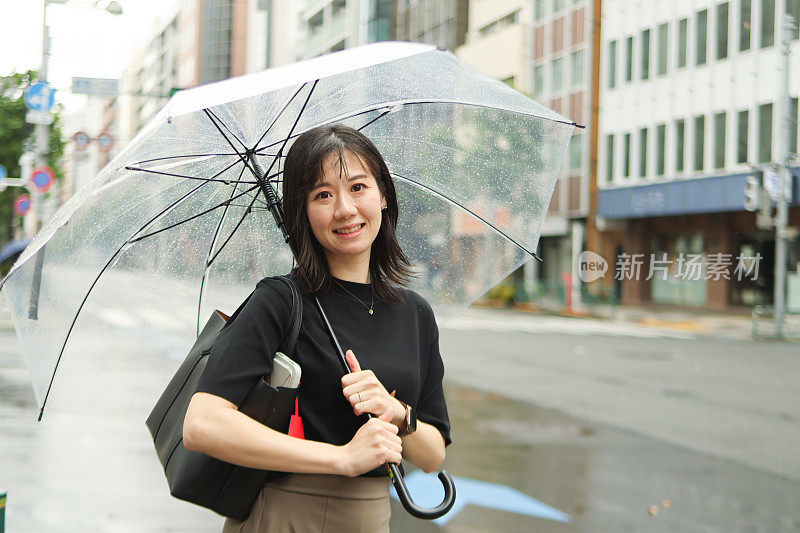 一个打着伞的漂亮的年轻女子站在街上