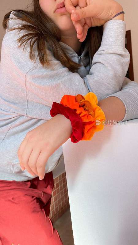 年轻的少女，手腕上系着红色和橙色的发带