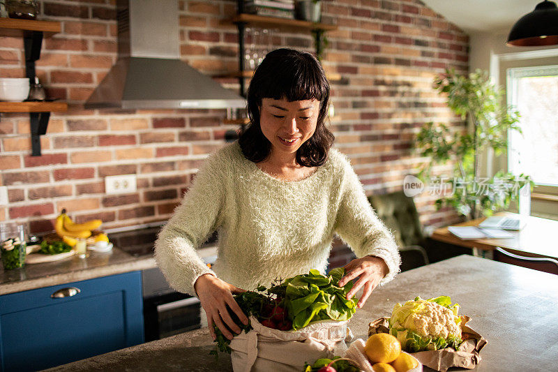 年轻的日本妇女在厨房里准备水果和蔬菜