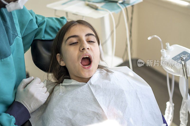 牙医在给一个女孩做牙科干预时带着一个病人