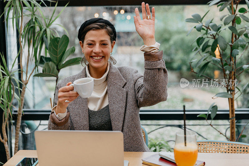 一位女士一边喝咖啡，一边用笔记本电脑进行视频会议或在线会议