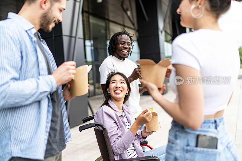 坐在轮椅上的年轻女子在户外和她的朋友们有说有笑