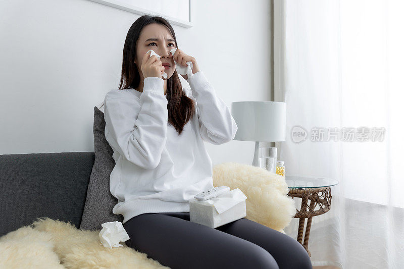 年轻漂亮的亚洲女孩坐在客厅舒适的沙发上看电视。