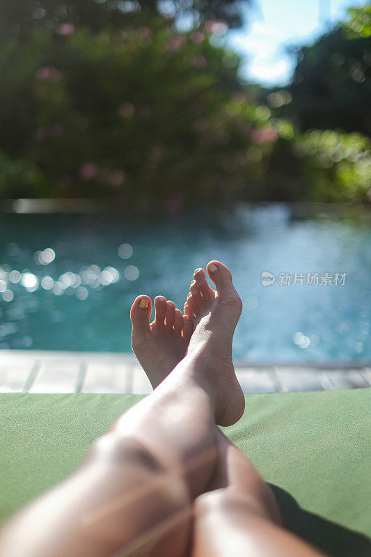 无法辨认的女人双腿交叉脚踝躺在日光浴躺椅上