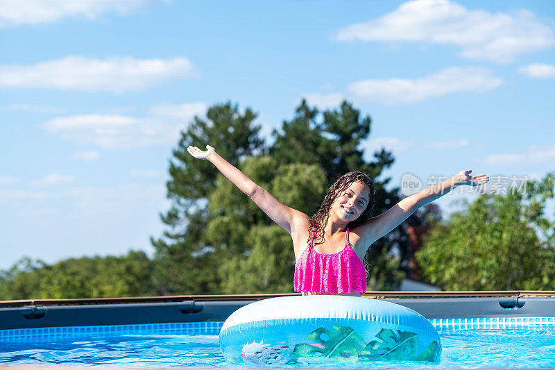 一个女孩在游泳池里高举双臂