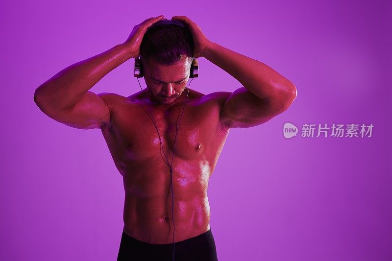 男子戴耳机运动体格健美者裸体躯干腹肌全长，健身类，紫色光。广告，运动，积极的生活方式，竞争，挑战的理念。