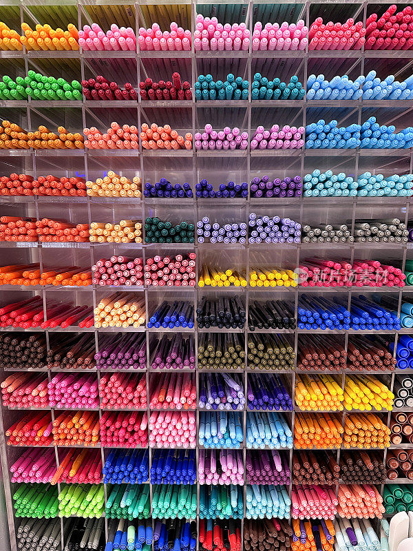 全帧图像零售货架单元墙包含文具，鸽子洞充满了五颜六色，毛毡尖笔，橙色，粉红色，绿色，红色和蓝色的笔出售，重点在前景