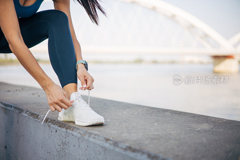 运动女性在户外练习前系鞋带的特写