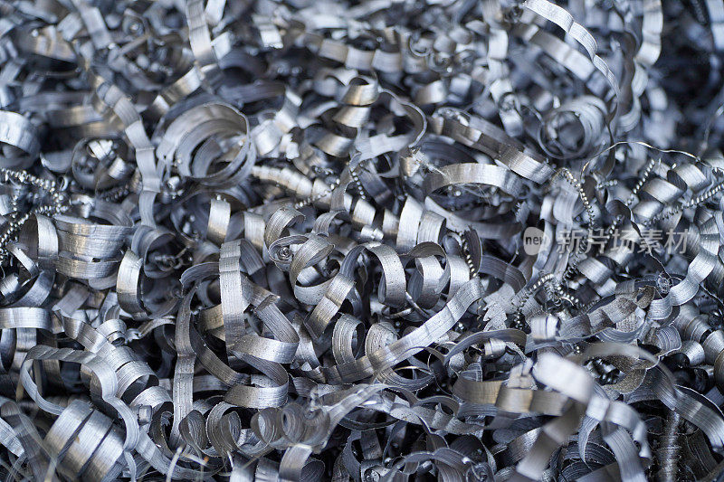 钢铁废料回收。在数控车床上加工金属零件后产生的铝屑。特写扭曲螺旋钢刨花。小粗糙度锐度，