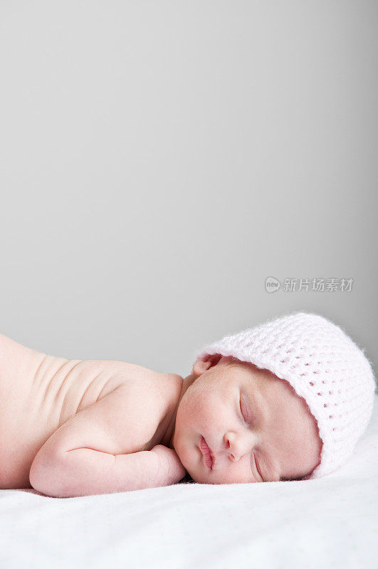戴着粉色帽子睡着的新生女婴