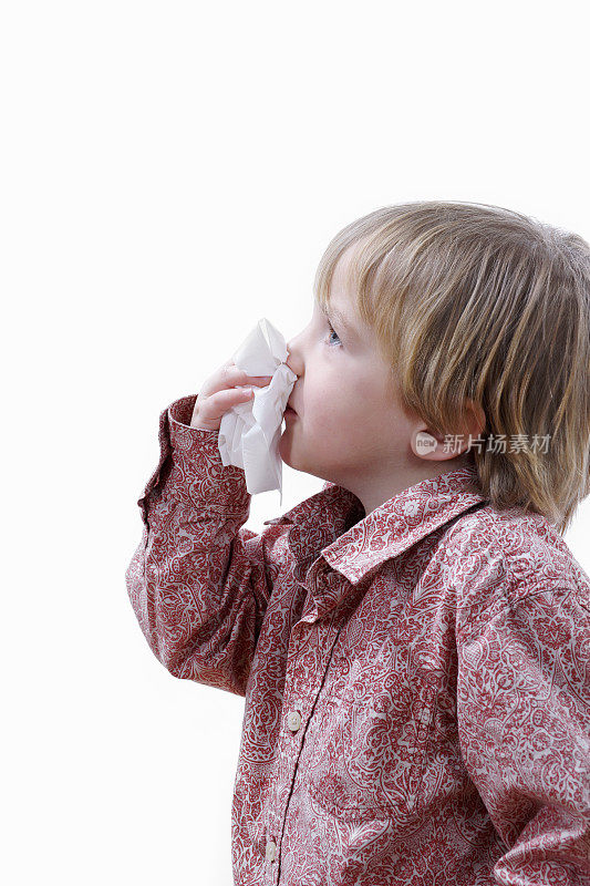 感冒的小男孩用白色的鼻子擤鼻涕