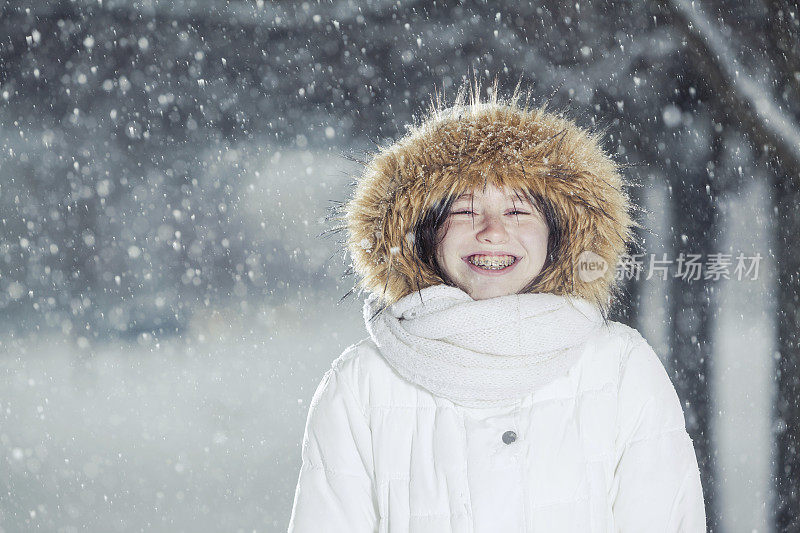 雪下穿着白色夹克的漂亮少女