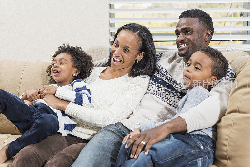 年轻的非洲裔美国人家庭在客厅的沙发上看电视