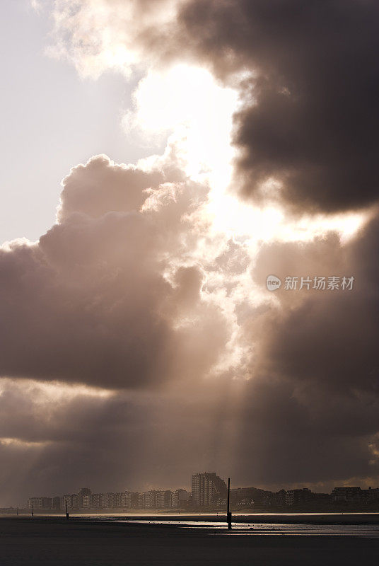 海滩上空戏剧性的天空，阳光透过云层，神秘莫测