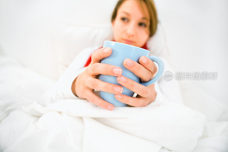 得了流感的女人坐在床上喝茶