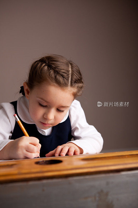 年轻女孩学生坐在课桌上写作