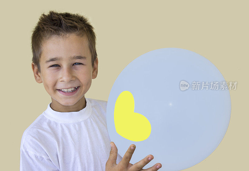 一个小男孩在彩色背景下拿着一个气球的肖像