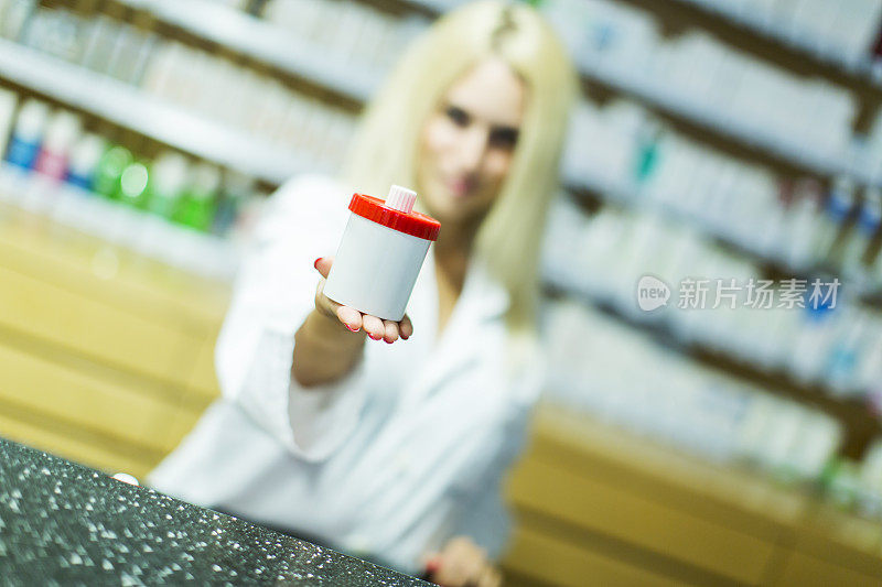 可爱的女药剂师拿着装有药物的容器对着镜头