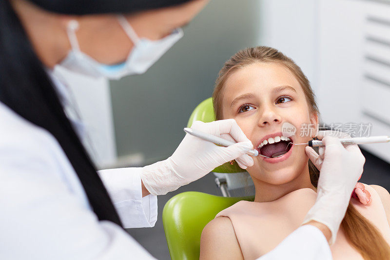 到牙科诊所进行牙齿检查。牙医检查女孩牙齿