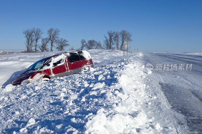 一辆小货车被困在高速公路边一条满是雪的沟里