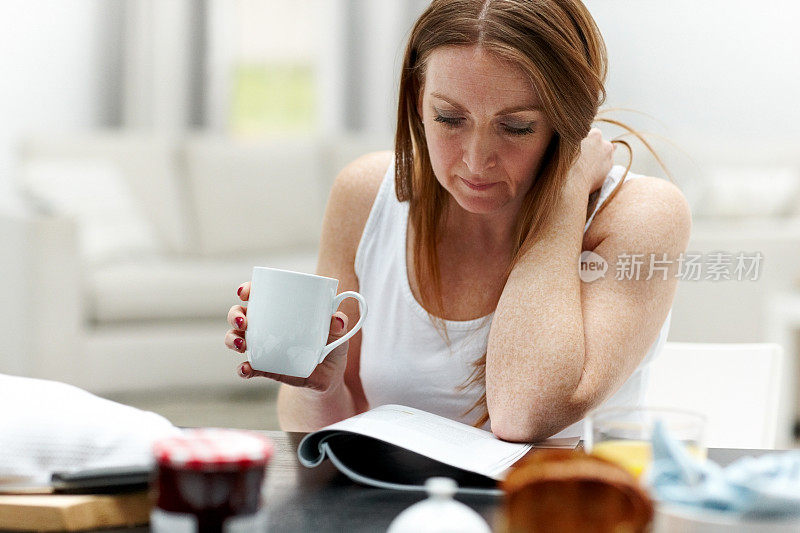 轻松成熟的女人一边喝咖啡一边看杂志