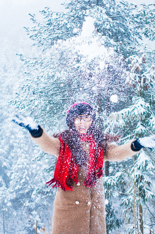 年轻女子在冬天的森林里玩雪