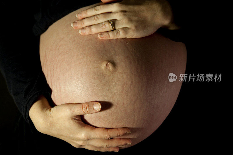 戏剧性的双手在怀孕的腹部黑色