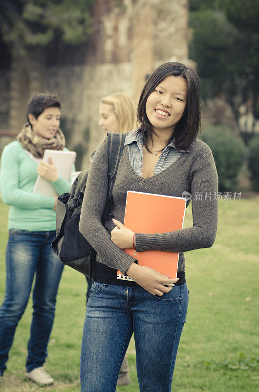 亚洲女大学生在户外拿着一本书