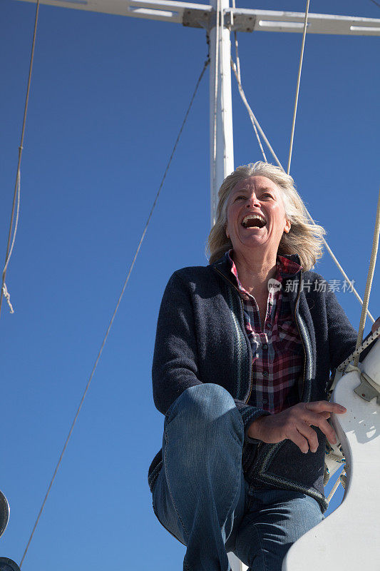 快乐的中年女水手在调整游艇上的索具