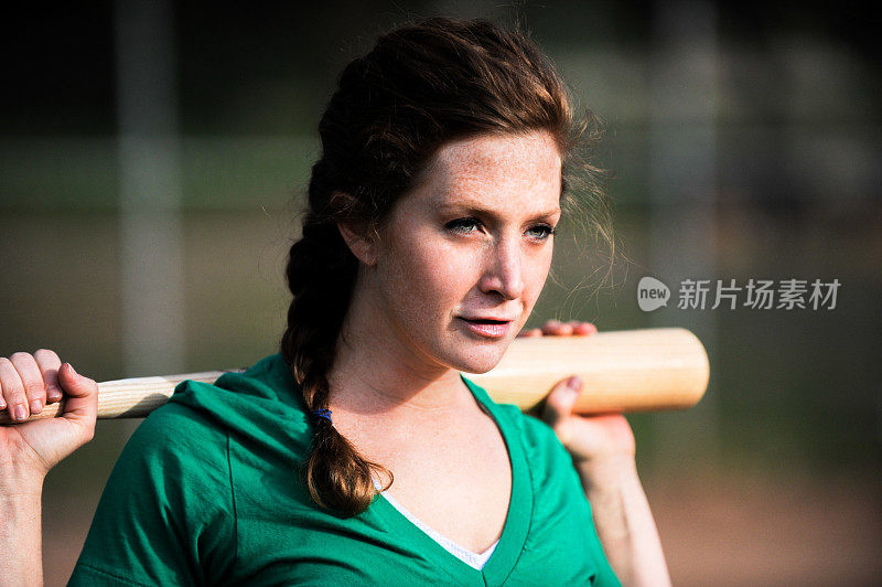 年轻女子垒球运动员，肩扛球棒