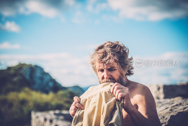 年长白人男子在徒步旅行时换衬衫